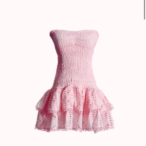 Design by Amor THYRA - sommarklänning med volanger - Supersöt rosa axelbandslös klänning med smockad överdel och volangig kjol. Klänningen är perfekt för dig som vill sticka ut med en feminin stockholmsstil. Jag säljer klänningen då den är för stor för mig, den är endast använd 2 gånger 🥰Nypris 549 kr