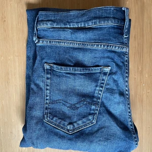 Replay Anbass jeans blå herr - Snygga blå Replay thad jeans med klassisk femficksdesign och raka ben. Jeansen har tydliga kontrastsömmar och en liten Replay-logga vid fickan. Tillverkade i slitstarkt denim med en bekväm passform som funkar till allt.