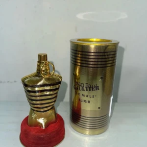 Jean Paul Gaultier Le Male Elixir - Exklusiv parfym i guldig metallflaska formad som en manlig torso, med matchande guldig cylinderförpackning. Le Male Elixir är en ikonisk doft med lyxig känsla och snygg design som sticker ut i badrumshyllan.