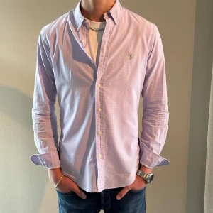 Ljuslila skjorta från Ralph Lauren - Hej! Säljer nu min fina Ralph Lauren-skjorta i storlek S (Slim Fit). Färg : Ljus lilla och vit i små små rutor. Modellen är 178cm lång. Skjortan är i bra skick och passar året om. Nypris cirka 1600 kr, ställ gärna frågor ✅