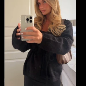 Svart omlottkofta med knytband - Mysig svart omlottkofta med knytband i midjan och långa ärmar. Koftan avönd 1 gång. Köparen står för frakten!