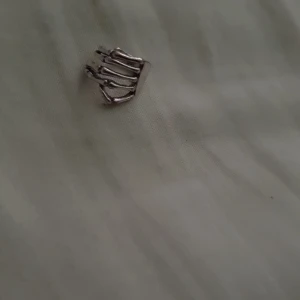 Silvrig öroncuff med ribbad design - Cool öroncuff i silverfärg med ribbad och öppen design. Den har flera smala band som ger ett trendigt och edgy intryck. Perfekt för dig som vill ha en snygg detalj utan att behöva hål i örat.