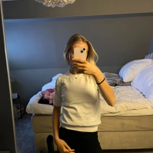 Vit stickad kortärmad tröja från Zara - Vit stickad tröja från Zara med rund halsringning och korta ärmar. Enkel och stilren modell som är lätt att matcha till olika outfits. Mjuk och skön kvalitet, perfekt för vår och sommar. Passar dig som gillar en clean och klassisk look.