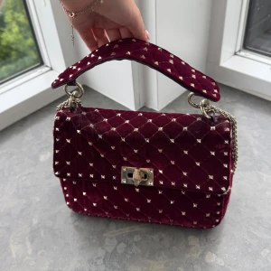 Rockstud valentino väska - Så snygg väska från valentino. Den är vällande och har några små defekter( fråga om bild) men de är inget som man lägger märket till tycker jag. Köpt vi Vestiaire där den har gått igenom en äkthets kontroll och bevis från den finns samt dustbag och serie nummer till väskan 💕
