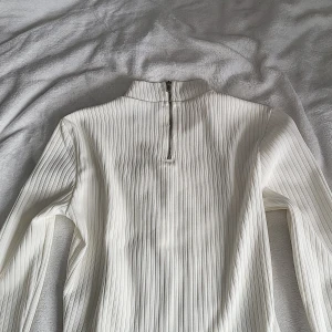 Vit ribbad långärmad tröja Forever 21 💗 - Vit ribbad långärmad tröja från Forever 21 med hög krage och dragkedja i halsen. Tröjan har en clean och stilren look med smala vertikala ränder och är gjord i ett stretchigt material som sitter snyggt på kroppen. Har en pytteliten färgskillnad men går nog bort 💗