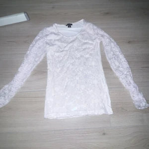 Vit spetsblus från Amisu XS - Supersöt vit blus från Amisu i storlek XS. Hela toppen är täckt av spets med blommigt mönster och har långärmade ärmar. Perfekt för dig som gillar romantisk och feminin stil. Sitter snyggt och är lätt att matcha med både jeans och kjol.