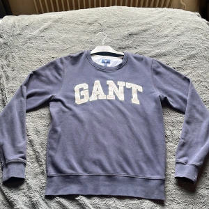 Blå sweatshirt från GANT med tryck - Säljer en blå sweatshirt från GANT i storlek M (passar även S) Mjuk och skön bomullskvalitet, perfekt för en chill och stilren look. Något utöver den klassiska tråkiga gant tröjan, unik, snygg och väldigt stilren. Kan bäras finklätt till middag men likaså en chill kväll vid grillen. Tröjan är en äldre modell så ordinarie pris är inte helt säkert (gissar runt 1200:-) trots äldre modell så är skicket otroligt bra och tröjan är väl bevarad. Säljer för 199:-