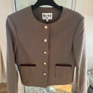 NYTT-Jacka med litet rutmönster stl 32 NAKD. Stor i storleken , stor i storleken  - Jacka med litet rutmönster Den här jackan har en kort passform och ett hundtandsmönstrat rutigt mönster. Den har en rundhals och öppna, små framfickor. Vår jacka har en knappstängning ner längs framsidan. Den här jackan kommer i rutig. Komposition: Yttertyg: 96% Polyester, 4% Elastan Foder: 100% Polyester