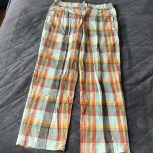 Rutig linnebyxa från H&M Edition - Färgglada linnebyxor från H&M Edition med rutigt mönster i mintgrönt, orange, gult och brunt. Byxorna har raka ben, dragkedja fram och bakfickor med knapp. Perfekta för dig som gillar statement-plagg och sköna material.