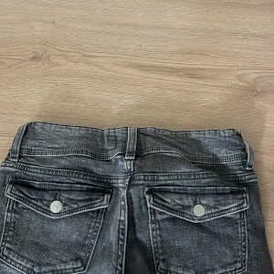 Svarta bootcut jeans Gina Tricot 158 - Snygga svarta bootcut jeans från Gina Tricot i storlek 158. Jeansen har en tvättad look, dubbla knappar i midjan och fickor med lock och knapp bak. Klassisk femficksmodell i stretchig denim som sitter skönt och ger en cool vibe.