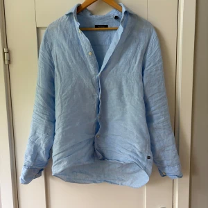 Ljusblå linneskjorta - Snygg ljusblå skjorta från Matinique i 100% linne. Perfekt nu till sommaren. Endast använd en gång i iprincip helt ny. Köptes ny för 1499kr säljer den nu för 699kr. Skriv vid frågor!