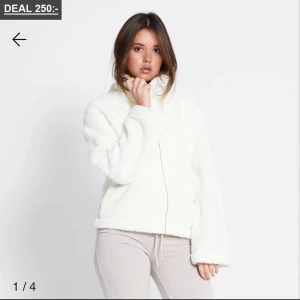 Vit teddyjacka med dragkedja - Mysig vit teddyjacka med dragkedja framtill och avslappnad passform. Jackan har lång ärm och fluffig textur som ger en cool och trendig look. Perfekt för att hålla värmen under kyliga dagar. Den är i storlek L men de känns som M 