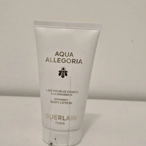 Aqua Allegoria Body Lotion Guerlain - Aqua Allegoria Bergamot Body Lotion från Guerlain i en vit tub med gulddetaljer. Lätt och fräsch doft av bergamott, perfekt för att återfukta huden och ge en lyxig känsla. Snygg minimalistisk design med guldfärgad text och ikonisk bi-symbol.