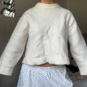 Vit fluffig stickad tröja mohair/wool blend - Mohair och ull blandning Supermjuk och fluffig vit stickad tröja med hög hals och långa ärmar. Tröjan har en lite boxig passform och ribbade muddar vid hals, ärmslut och nederkant. Perfekt för lager-på-lager och chill dagar. Tyvärr krympt lite i tvätten