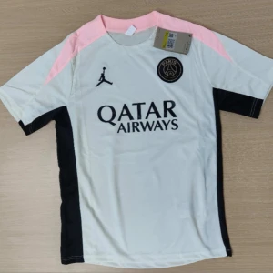 PSG x Jordan fotbollströja och shorts priset kan diskuteras  - Snygg PSG fotbollströja i vitt med svarta och ljusrosa detaljer, kortärmad och tillverkad i lätt, andasvänligt material. Matchande svarta shorts med rosa inslag och PSG-logga samt Jordan-logga. Perfekt för dig som vill sticka ut på planen.