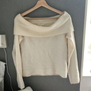 Offshoulder vit stickad tröja Gina Tricot - Superfin offshoulder stickad tröja från Gina Tricot i mjuk vit färg. Tröjan har bred ribbad kant upptill och vid ärmslut samt nederkant. Perfekt för dig som gillar en chill och trendig look med lite extra edge.