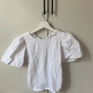 Vit puffärm blus från Zara - Supersöt vit blus från Zara med trendiga puffärmar och rund halsringning. Tillverkad i mjuk bomull som känns skön mot huden. Perfekt för dig som gillar en stilren look med lite extra volym på ärmarna. Passar till både jeans och kjol.