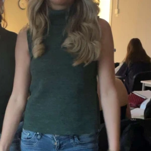 Polo topp från Zara  - Snygg mörkgrön polotopp med ärmlös design och hög krage. Perfekt att matcha med jeans eller kjol för en stilren look. Toppens material känns mjukt och har en lätt stickad känsla. Skönt nu till hösten!