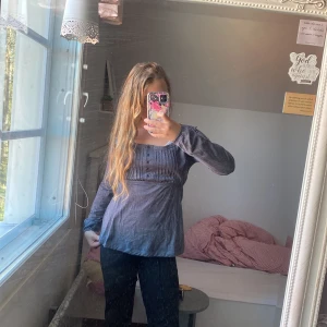 Grå långärmad topp från B-Soul - Mjuk och bekväm grå långärmad topp från B-Soul i storlek S. Toppen har knappar framtill och fina sömdetaljer vid bröstet. Perfekt för en avslappnad stil och passar bra till jeans.