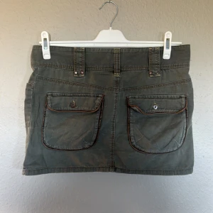 Grå jeanskjol från Bik Bok - Säljer en grå jeanskjol från Bik Bok med två stora fickor bak och klassiska jeansdetaljer. Kjolen är kort och har bälteshällor samt knapp- och dragkedjestängning framtill. Perfekt för dig som gillar en enkel och cool stil. 45 cm rakt över midjan 
