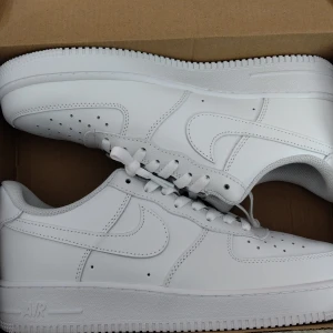 Nike Air Force 1 helvita sneakers - Säljer ett par feta helvita Nike Air Force 1 sneakers. Skorna har en stilren design med rund tå, snörning och platt sula. Perfekta för dig som gillar en clean och tidlös look. Kommer i originalkartong.