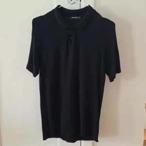 Tiger of Sweden pikétröja strl.S - Klassisk svart pikétröja från Tiger of Sweden med krage och knappar framtill. Tillverkad i mjukt material som känns skönt mot huden. Perfekt för en stilren och enkel look.