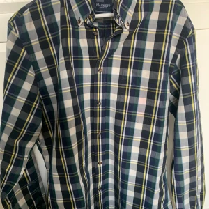 Rutig skjorta från Hackett London - Snygg rutig skjorta från Hackett London i blått, grönt, vitt och gult. Skjortan har lång ärm, klassisk krage med knappar och är tillverkad i bomull. Perfekt för dig som gillar stilrena och tidlösa plagg.