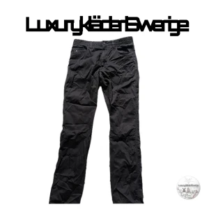 J.Lindeberg byxor - Svarta kostymbyxor från J.Lindeberg i slim fit-modell. Klassisk design med raka ben och diskreta fickor. Perfekta för en stilren och modern look. Byxorna har en enkel midja och är tillverkade i ett mjukt material som ger en bekväm känsla.