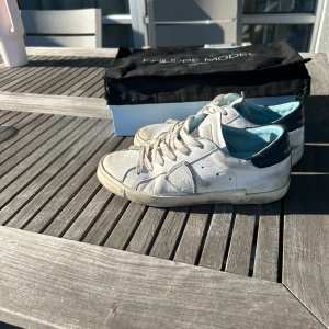 Vita Philippe model  - Säljer ett par vita Philippe Model sneakers med svarta detaljer. Perfekta för dig som gillar stilrena och bekväma sneakers. Passar perfekt till sommaren/våren. Allt OG kommer med.Bara att höra av sig vid minsta fundering. Priset går att diskuteras vid snabb affär.