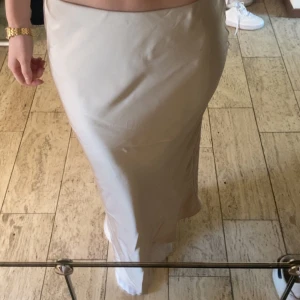 Beige satinkjol från Zara - Säljer en beige/rosa långkjol i satin från Zara. Kjolen har en slät och glansig yta med en elegant, rak passform som faller snyggt längs kroppen. Perfekt för dig som gillar stilrena och enkla plagg med lyxig känsla. Helt oanvänd🤍