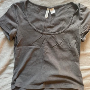 Grå croppad t-shirt från Chiquelle - En enkel grå croppad t-shirt från Chiquelle med rund halsringning och korta ärmar. Perfekt till jeans eller kjol för en avslappnad stil.