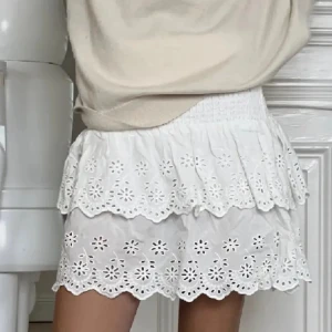 Vit volangkjol med broderade detaljer - Supersöt vit kjol med volanger och broderade blommor. Kjolen har en smockad midja som gör den bekväm och sitter snyggt. Perfekt till sommaren och ger en romantisk vibe till outfiten💕💕