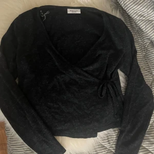 Svart omlottopp från Kappahl - Svart omlottopp från Kappahl med långa ärmar och knyt i sidan. Tunn och mjuk kvalitet, perfekt att styla till olika outfits. Klassisk och enkel design som passar till mycket. Helt oanvänd💕