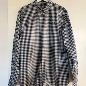 Ny Fred Perry blåvit herr skjorta, storlek 42 - •Den här Fred Perry Gingham-skjortan är en klassisk pjäs med en modern twist. Gingham-mönstret ger en touch av stil, medan de långa ärmarna och knappnedslagna kragen ger ett polerat utseende. •Skjortan är gjord av högkvalitativa material och är designad för att vara bekväm och hållbar.  •Material: 100% bomull. •Helt ny, endast tvättad. •Köpte för 1999 kr. •Djurfritt och rökfritt hem.