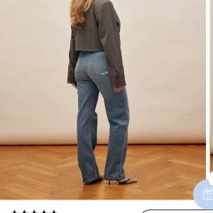 Blå jeansbyxor från OLIVER AVENUE - Säljer ett par jeansbyxor från Djerf Avenue med broderad logga och röd hjärtdetalj på bakfickan. Byxorna har normal passform och raka ben, perfekt för en avslappnad stil.