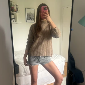 Beige ribbad polotröja från Vacancy - Säljer en beige ribbad polotröja från Vacancy by Carly Gry. Tröjan har trekvarts ärm och hög krage, passar till allt. Tröjan är gjord i 80% ull