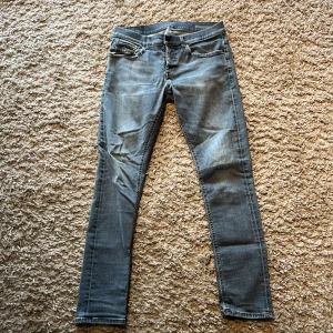 Grå Dondup jeans - Säljer ett par grå dondup jeans med slitna detaljer på baksidan. Byxorna har klassisk femficksdesign. Byxorna har lagade hål på baksidan så dem kommer inte gå sönder nått mer 