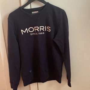 Mörkblå sweatshirt från Morris - Säljer en mörkblå sweatshirt från Morris med vit text 'MORRIS SINCE 1968' på bröstet. Tröjan har rund halsringning och långa ärmar. Perfekt för en avslappnad och stilren look.