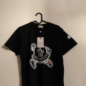 Svart t-shirt från Moncler - Hej! Säljer nu en Moncler T-shirt som är i väldigt fint skick och väldigt stilren, snabb och smidig affär vid rätt pris!                                                                ⚠️‼️BYTEN ÄR INTRESSANT‼️⚠️