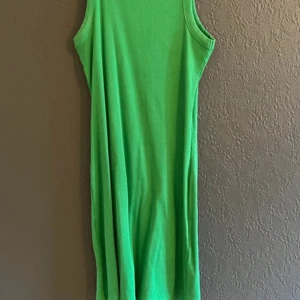 Grön ribbad ärmlös klänning från BikBok - Säljer en grön ribbad klänning från BikBok. Klänningen är ärmlös med rund halsringning och har en enkel, rak passform. Perfekt för varma dagar och enkel att styla med sneakers eller sandaler. Använd 1-2 gånger