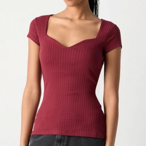 Vinröd topp - Säljer en vinröd ribbad topp från Anna Field med v-ringning och korta ärmar. Toppen har en figurnära passform och är tillverkad i ett stretchigt material.