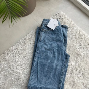 Blå jeansbyxor Regular Wide från Never Denim 🌸 - Säljer ett par blå jeansbyxor från Never Denim i modellen Regular Wide. Byxorna har aldrig använts. Byxorna är hög midjade och raka, vida nertill. Klassisk femficksmodell med dragkedja och en knapp framtill. Perfekta för en avslappnad och trendig look.