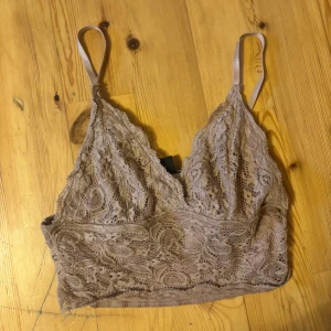 Beige spets bralette från Amisu - Säljer en rosa croppad top från Amisu i storlek XS. Toppen är helt i spets med v-ringning och justerbara axelband. Perfekt för lager-på-lager