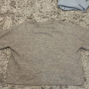 Beige stickad tröja från 157 - Mysig beige stickad tröja från 157 i storlek M. Tröjan har rund halsringning och långa ärmar, perfekt för lager-på-lager. Enkel och stilren design som passar till det mesta.