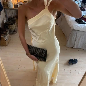Gul balklänning - Säljer en ljusgul långklänning med one shoulder och knytning på axeln. Klänningen har en elegant och smickrande passform med slits i sidan. Perfekt för sommarens tillfällen. Materialet känns mjukt och följsamt. Jag är 176 cm lång och brukar ha xs/s. Inga defekter, helt ny