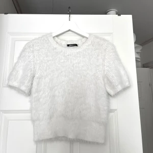 Vit fluffig stickad tröja från Gina  - Säljer en söt vit stickad tröja från Gina Tricot. Tröjan har korta ärmar och en rund halsringning, supermjukt material. Något liten i storlek, storlek M men passar mer xs/s