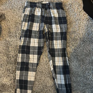 Pyjamasbyxor  - Snygga mysiga pyjamasbyxor med svart, grått och vitt rutmönster. De har en avslappnad passform och resår i midjan för extra komfort. Perfekta för en chill vardagslook eller som mjukisbyxor hemma.