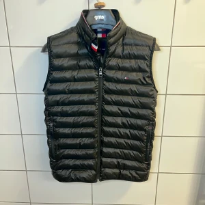 Dunväst - Tommy Hilfiger - Fräsch dunväst från Tommy Hilfiger med dragkedja framtill och två fickor med dragkedja. Västen är lätt och tillhör TH Packable Series, vilket gör den smidig att ta med. Perfekt för lager-på-lager under kyliga dagar.