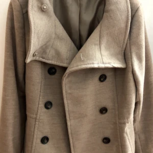 Beige kappa med dubbelknäppning - Snygg beige kappa  med  dubbelknäppning framtill. Sitter jätte fint på kroppen 💗Knappt använd så den är i väldig bra skick. Köpt för 600kr💗Skicka GÄRNA prisförslag 