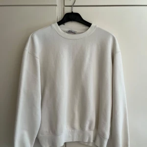 Vit sweatshirt från Zara - Säljer en klassisk vit sweatshirt från Zara i storlek M. Tröjan har rund halsringning, långa ärmar och ribbade muddar vid ärmslut och nederkant. Perfekt basplagg i mjukt material. Säljer då den inte pasar mig.